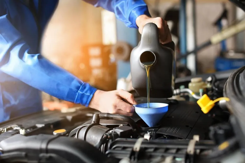 Mechaniker füllt in einem Servicecenter Autoöl nach