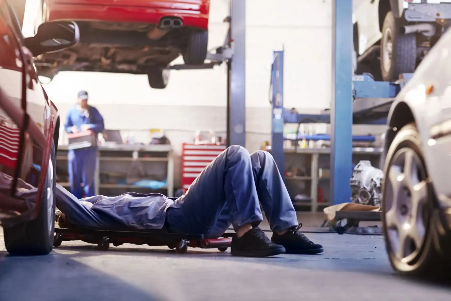 Mechaniker unter einem Auto in einer Autowerkstatt